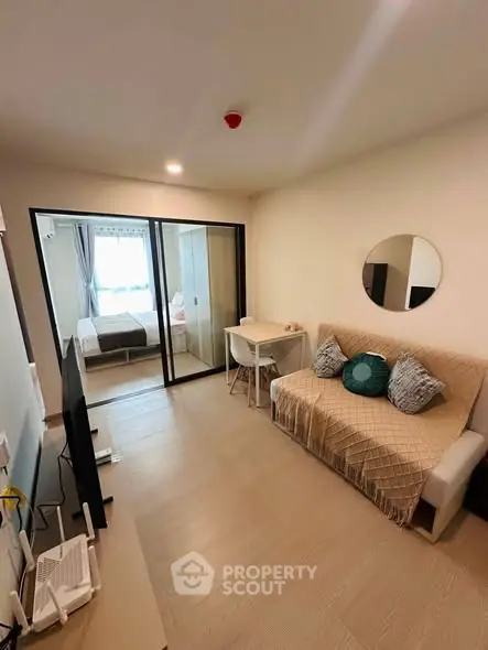 Modern living room with cozy sofa, stylish decor, and sliding glass doors leading to a bright bedroom.