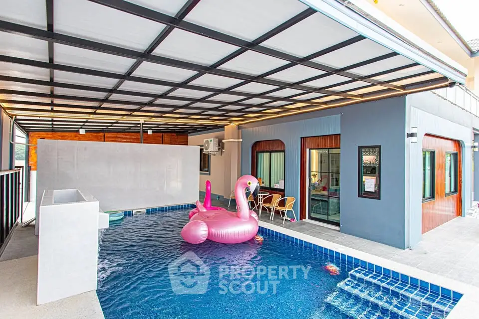 Modern covered pool area with playful pink flamingo float and stylish architecture.