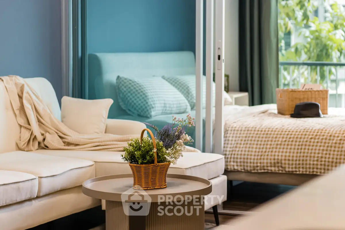 Chic modern living room with cozy bedroom view, stylish decor, and lush greenery outside.