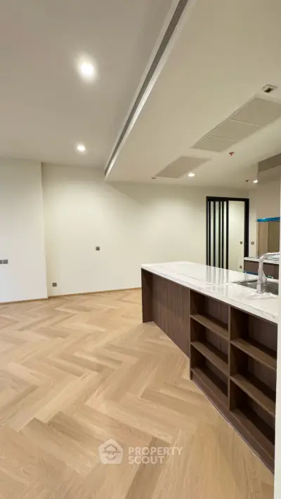 Spacious modern kitchen with elegant wooden flooring and sleek marble countertop.