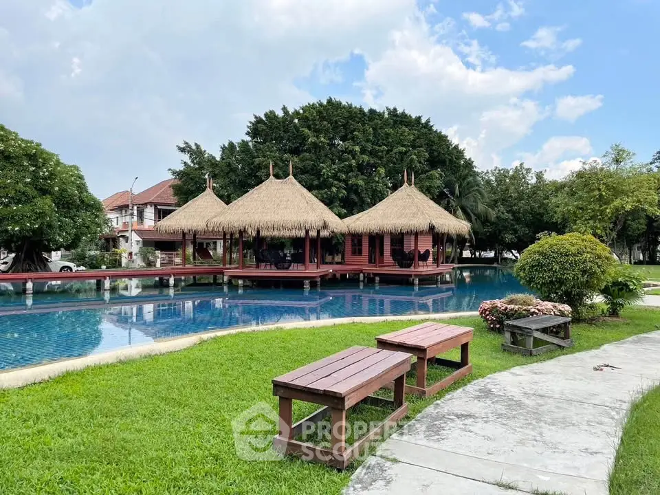 Stunning tropical poolside view with traditional thatched-roof pavilions and lush greenery.