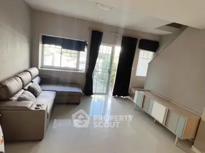 Spacious living room with modern sofa and natural light, perfect for relaxation and entertainment.