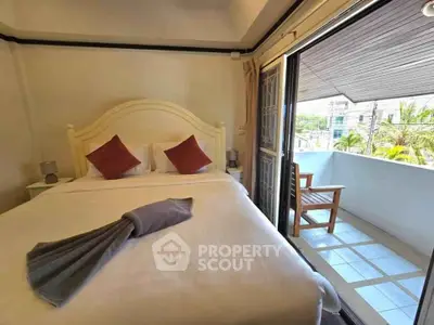 Cozy bedroom with balcony access and outdoor seating in a modern apartment.