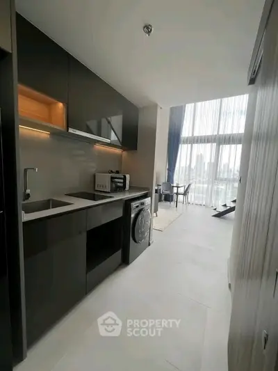Modern kitchen with sleek appliances and open layout leading to bright living area with city view.