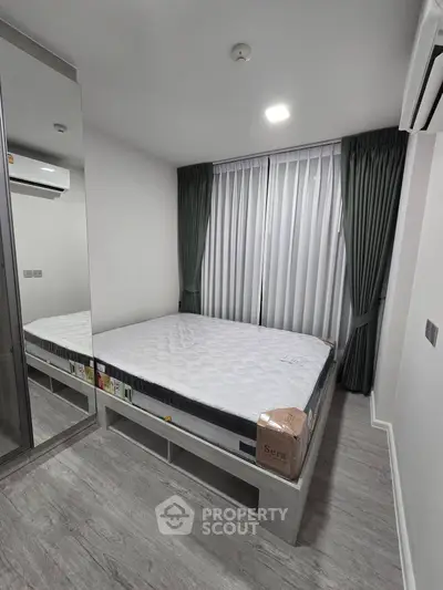 Modern bedroom with sleek design, featuring a mirrored wardrobe and elegant curtains.