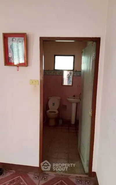 Cozy bathroom with pink tiles and essential fixtures in a compact space.