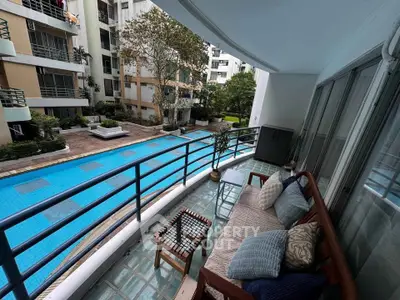 Spacious balcony overlooking a serene pool in a modern apartment complex.