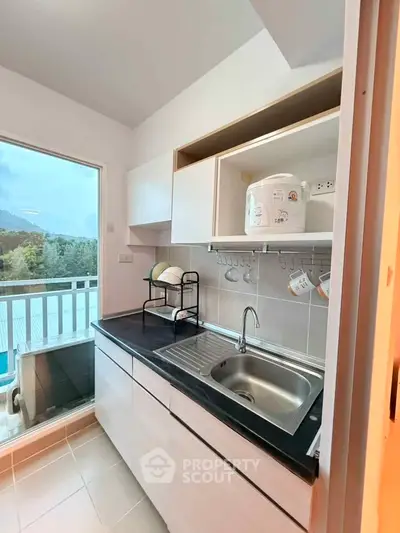 Modern kitchen with sleek cabinetry and scenic balcony view, perfect for culinary enthusiasts.