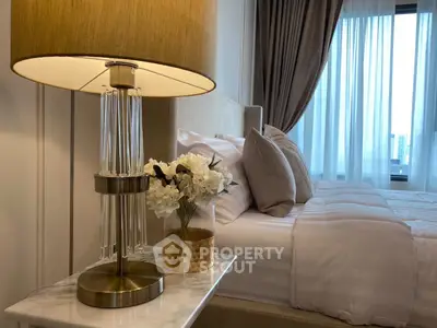 Luxurious bedroom with elegant decor and cozy ambiance, featuring a stylish lamp and plush bedding.