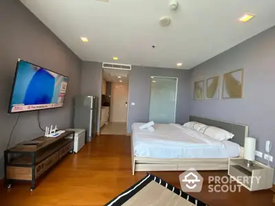 Spacious modern bedroom with wooden flooring and wall-mounted TV in luxury apartment.