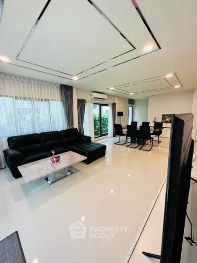 Spacious modern living room with sleek black furniture and large windows.