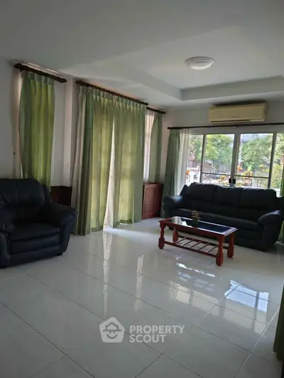 Spacious living room with large windows and comfortable seating, perfect for relaxation and entertaining.