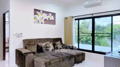 Modern living room with plush sofa and large window offering lush green views.