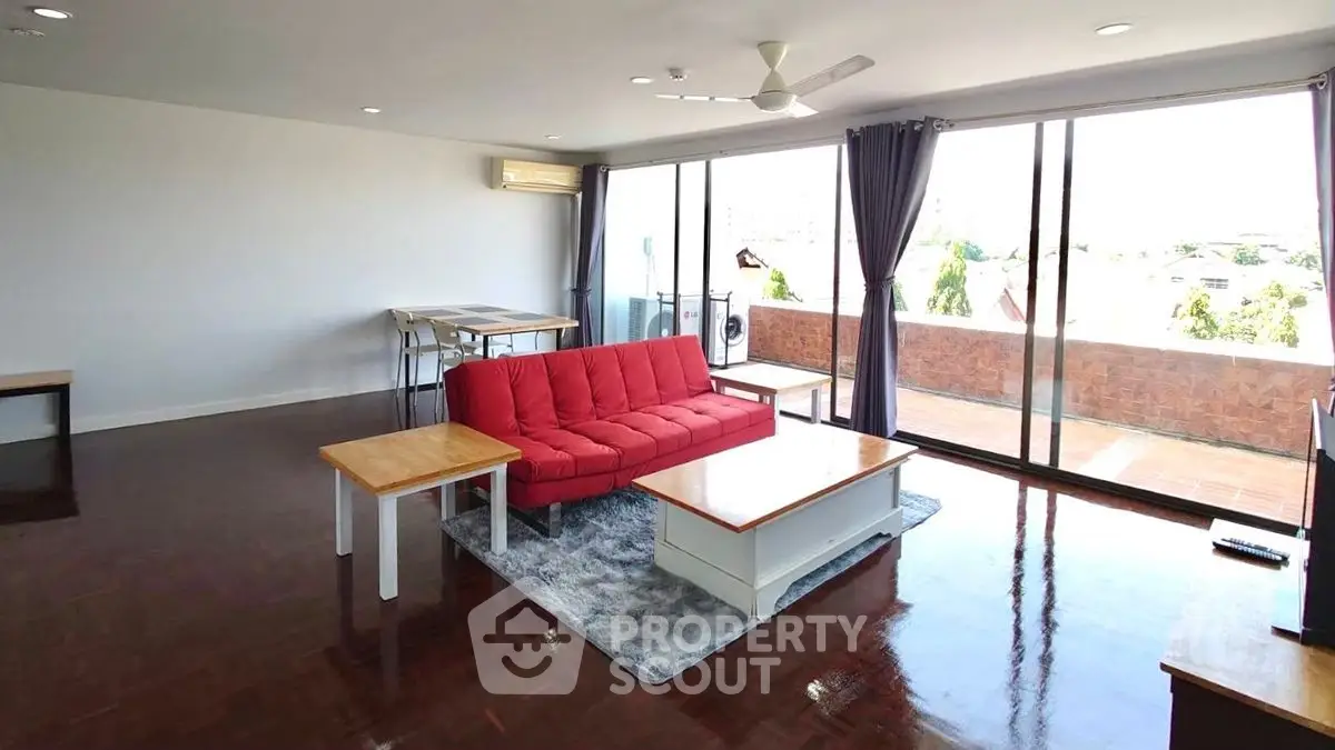 Spacious living room with red sofa and large balcony view
