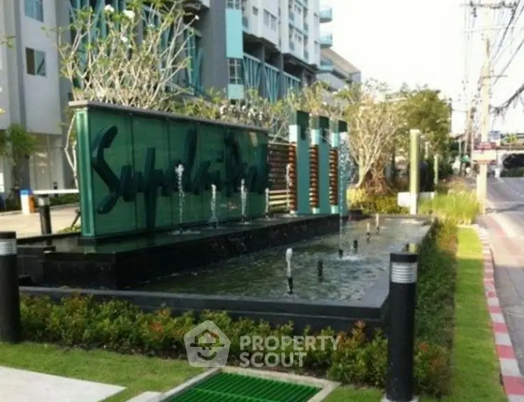 Modern building entrance with stylish water feature and lush landscaping.