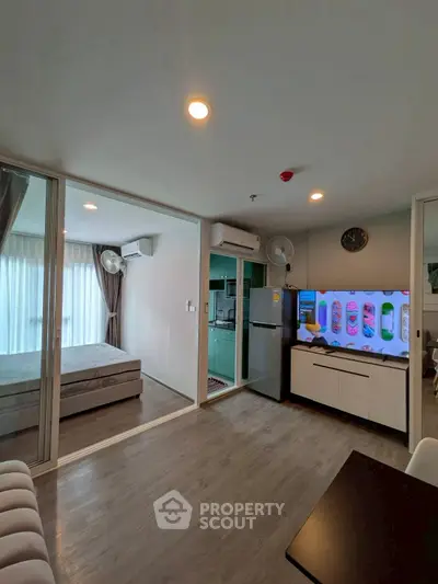 Modern open-plan living room with adjacent bedroom and sleek kitchen appliances.