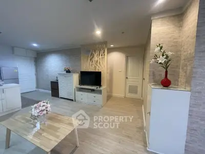 Spacious living room with modern decor and natural light, featuring a stylish TV unit and elegant wooden flooring.