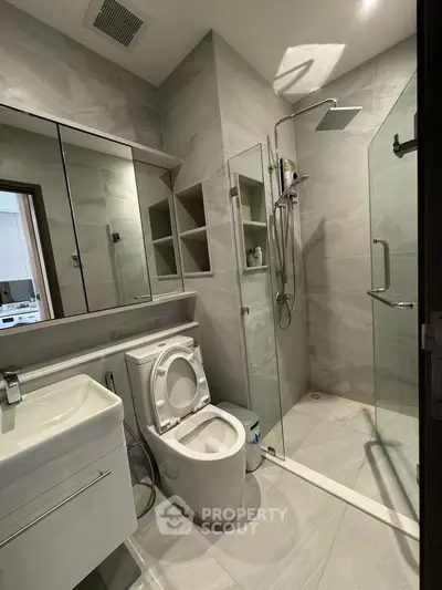 Modern bathroom with sleek design, featuring a glass shower enclosure and integrated storage solutions.