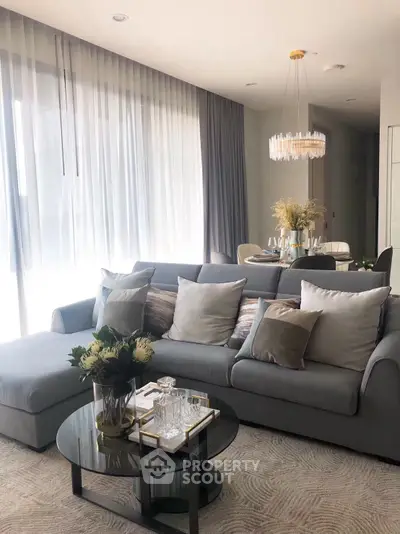 Elegant living room with plush sofa, modern chandelier, and floor-to-ceiling windows.