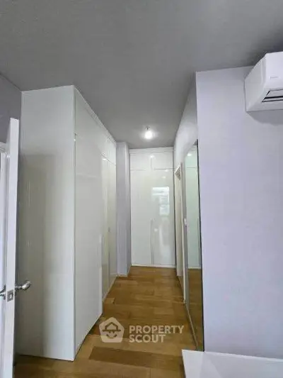 Modern hallway with sleek white storage and wooden flooring