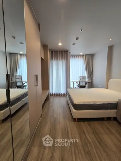 Modern bedroom with stylish decor and large window, featuring a comfortable bed and sleek wooden flooring.