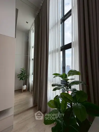 Modern interior with tall windows and lush greenery, offering a serene and airy ambiance.