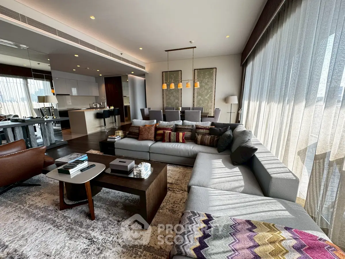 Luxurious modern living room with large sectional sofa and open kitchen layout, featuring floor-to-ceiling windows.