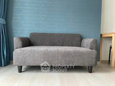Modern gray sofa in stylish living room with geometric blue accent wall