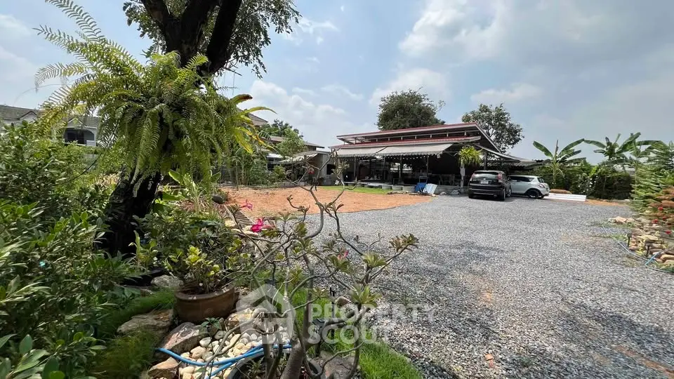 Spacious property with lush garden and ample parking space under a clear sky.