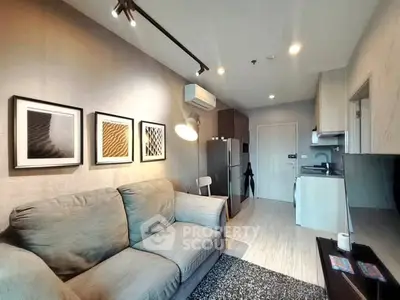 Modern living room with cozy sofa, stylish decor, and compact kitchen area in open layout apartment.