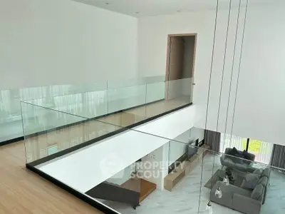 Modern open-concept living room with glass railing and high ceiling