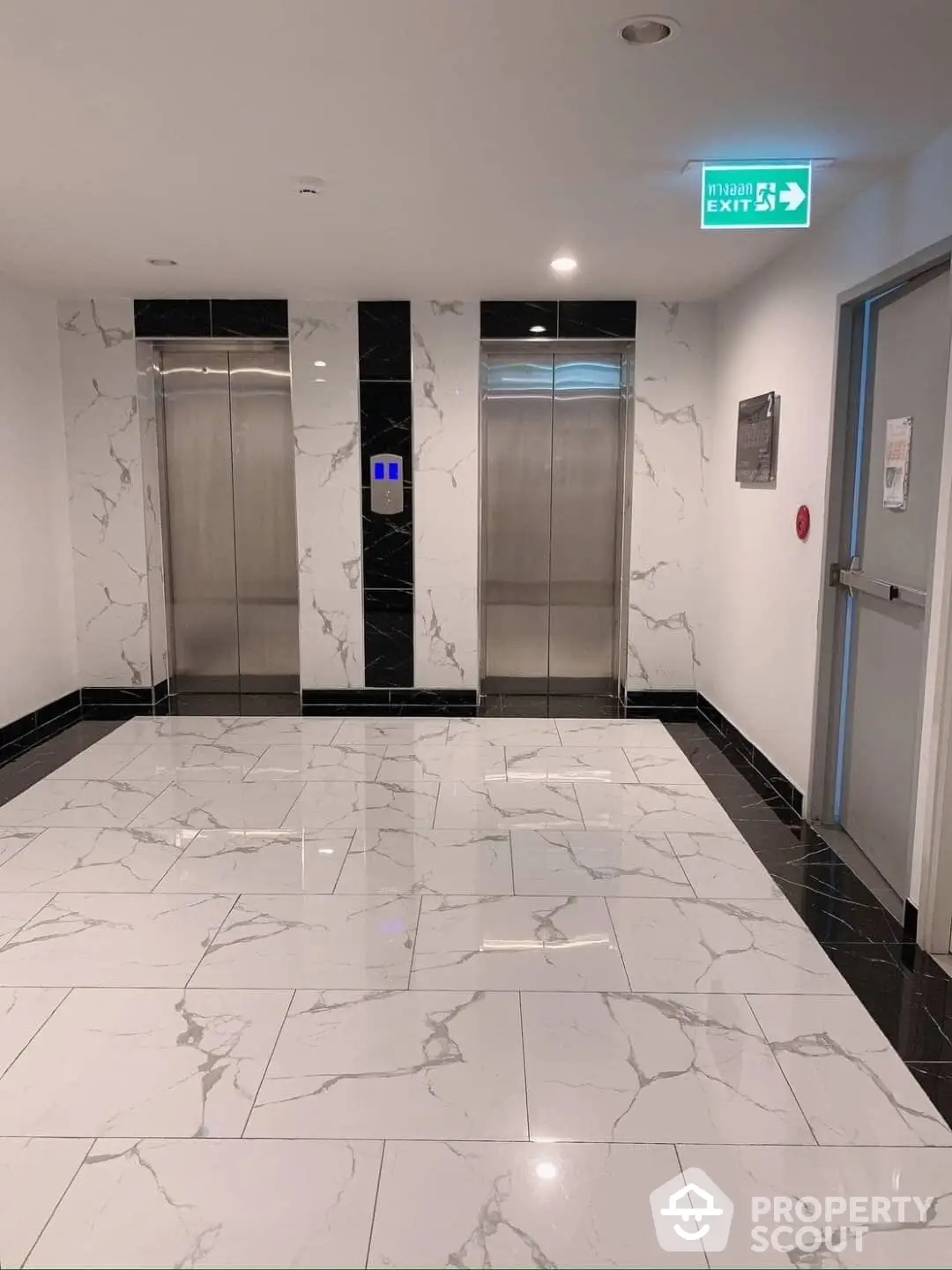 Elegant elevator lobby area with polished marble floors and modern stainless steel doors, reflecting upscale building amenities.