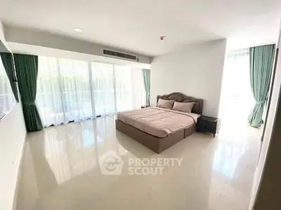 Spacious bedroom with large windows and elegant curtains in a modern apartment.