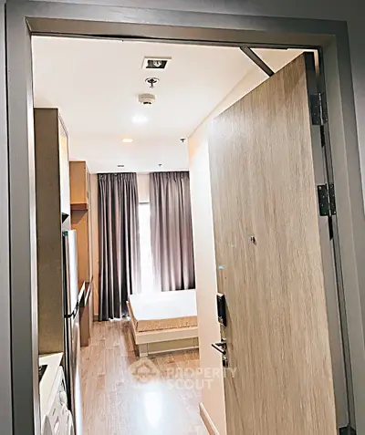 Modern apartment entrance leading to cozy bedroom with natural light and stylish decor.