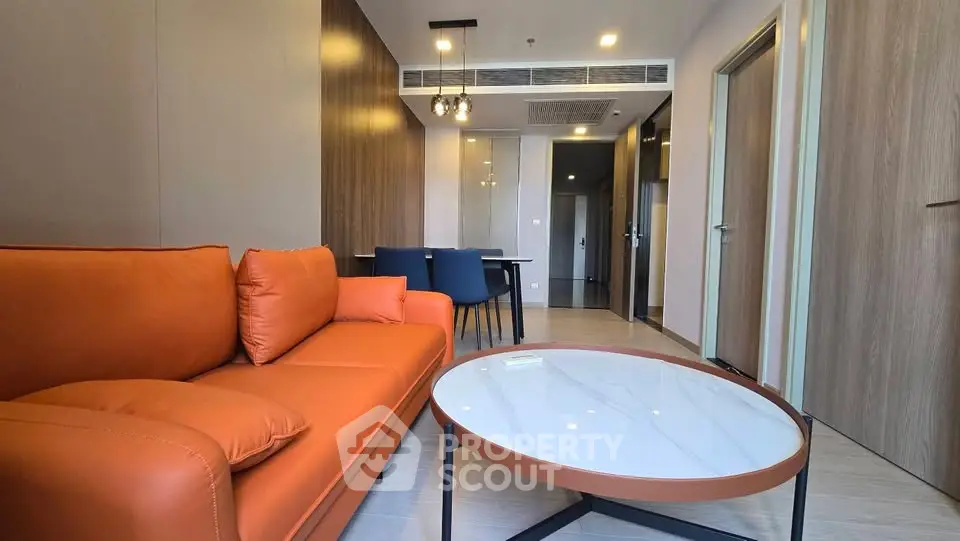 Modern living room with orange sofa and sleek decor in a stylish apartment.