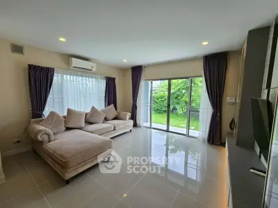 Spacious living room with large windows and garden view, featuring elegant furniture and modern design.