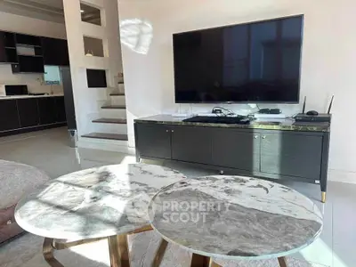 Modern living room with sleek TV setup and stylish marble tables