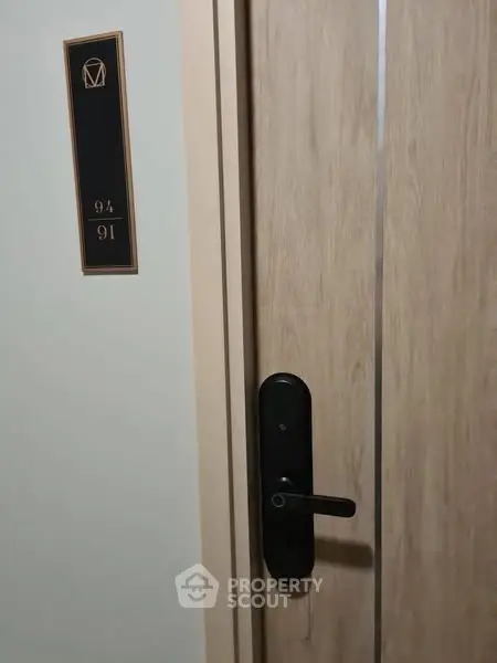 Modern apartment door with sleek black handle and room number plaque.