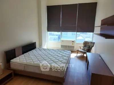 Spacious bedroom with large window and modern furnishings, perfect for comfort and relaxation.