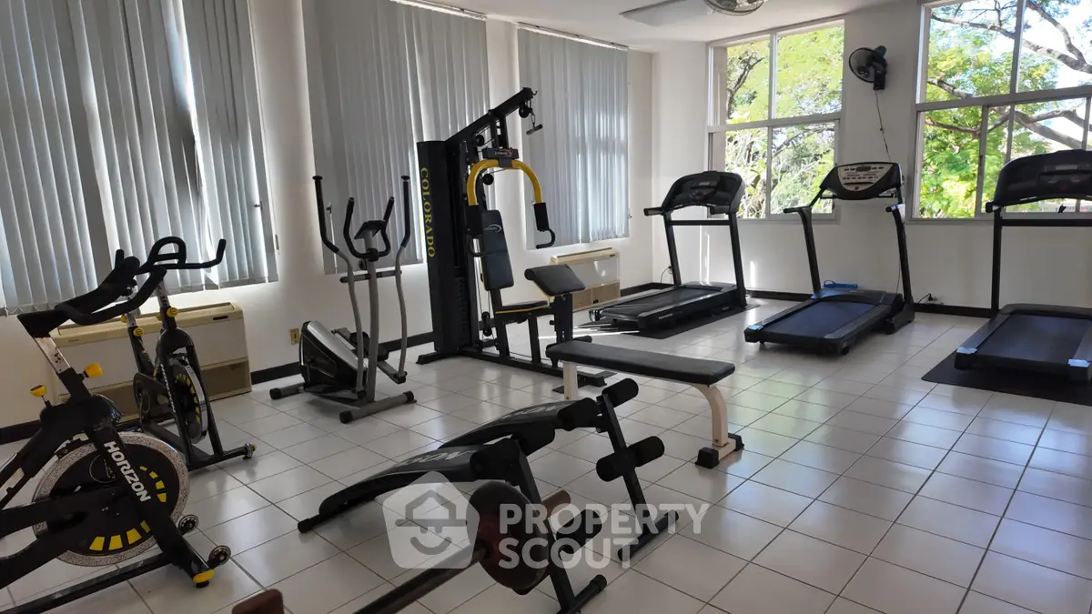 Spacious gym with modern equipment and large windows for natural light.