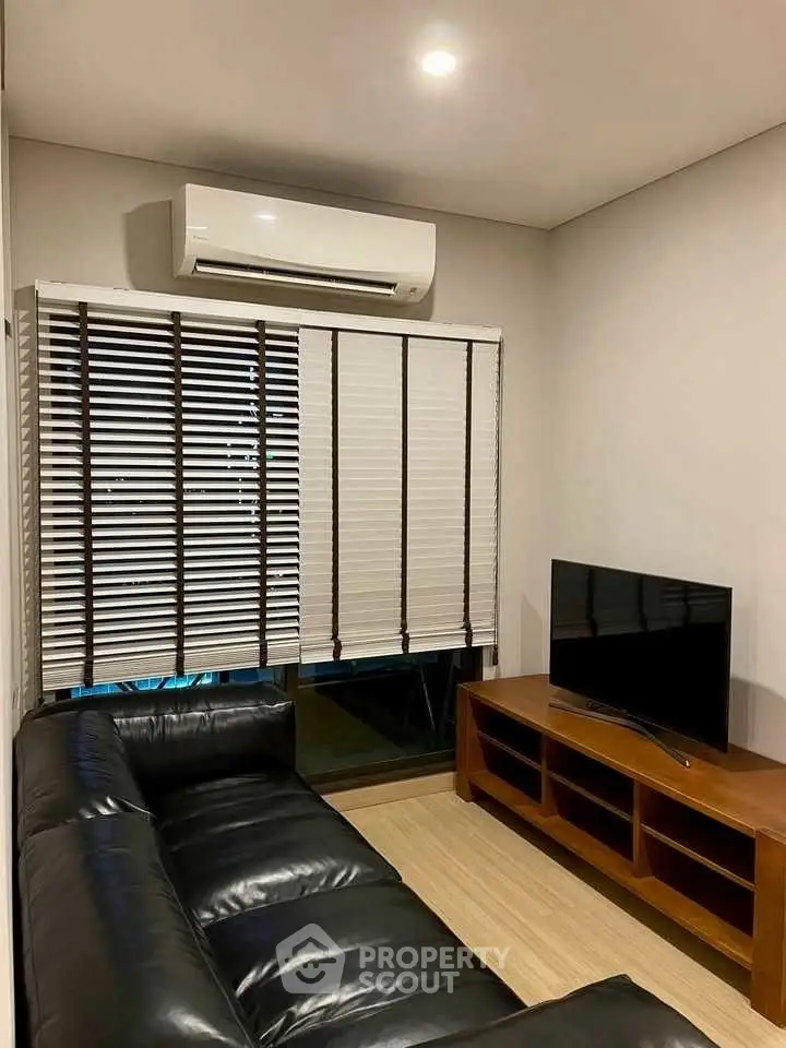 Cozy living room with leather sofa, TV, and air conditioning.