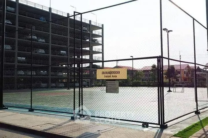 Spacious outdoor sports court next to multi-level parking structure.