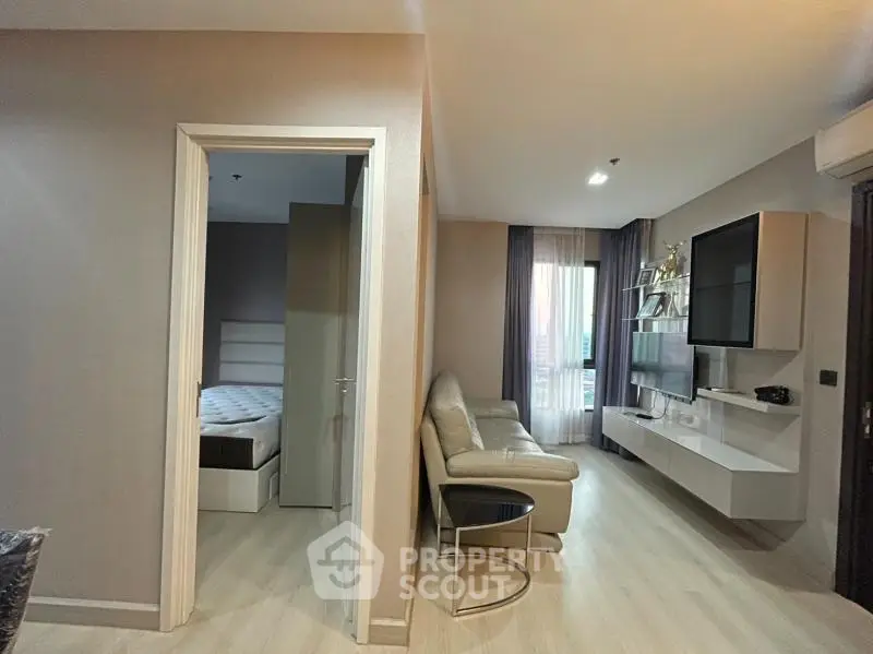 Modern living room with sleek furniture and adjacent bedroom in stylish apartment.