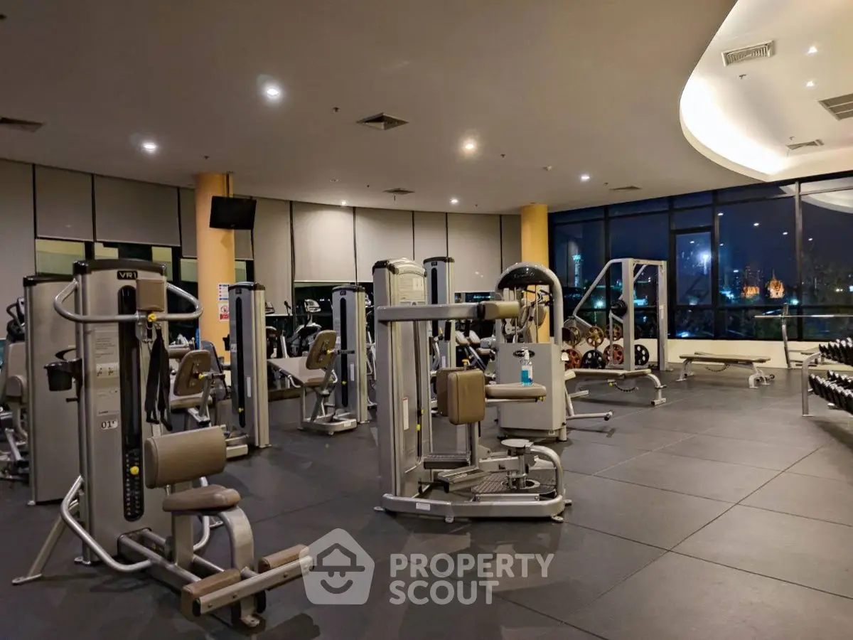 Spacious modern gym with state-of-the-art fitness equipment and large windows offering a city view.