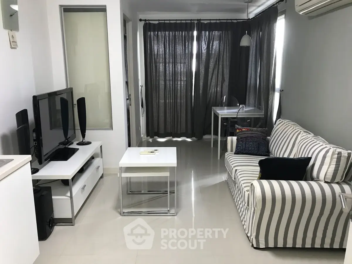 Modern living room with striped sofa and sleek TV setup in stylish apartment.