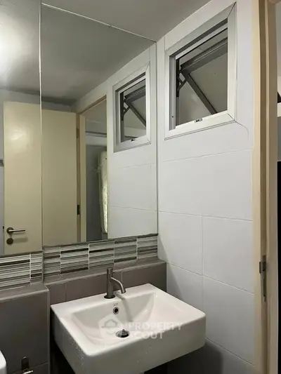 Modern bathroom with sleek sink and mirror, featuring contemporary design and natural light.