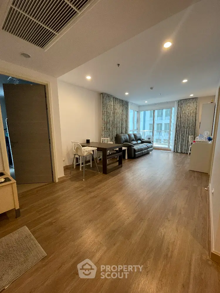 Spacious living room with modern furniture, hardwood flooring, and ample natural light from large windows, perfect for family gatherings and relaxation.