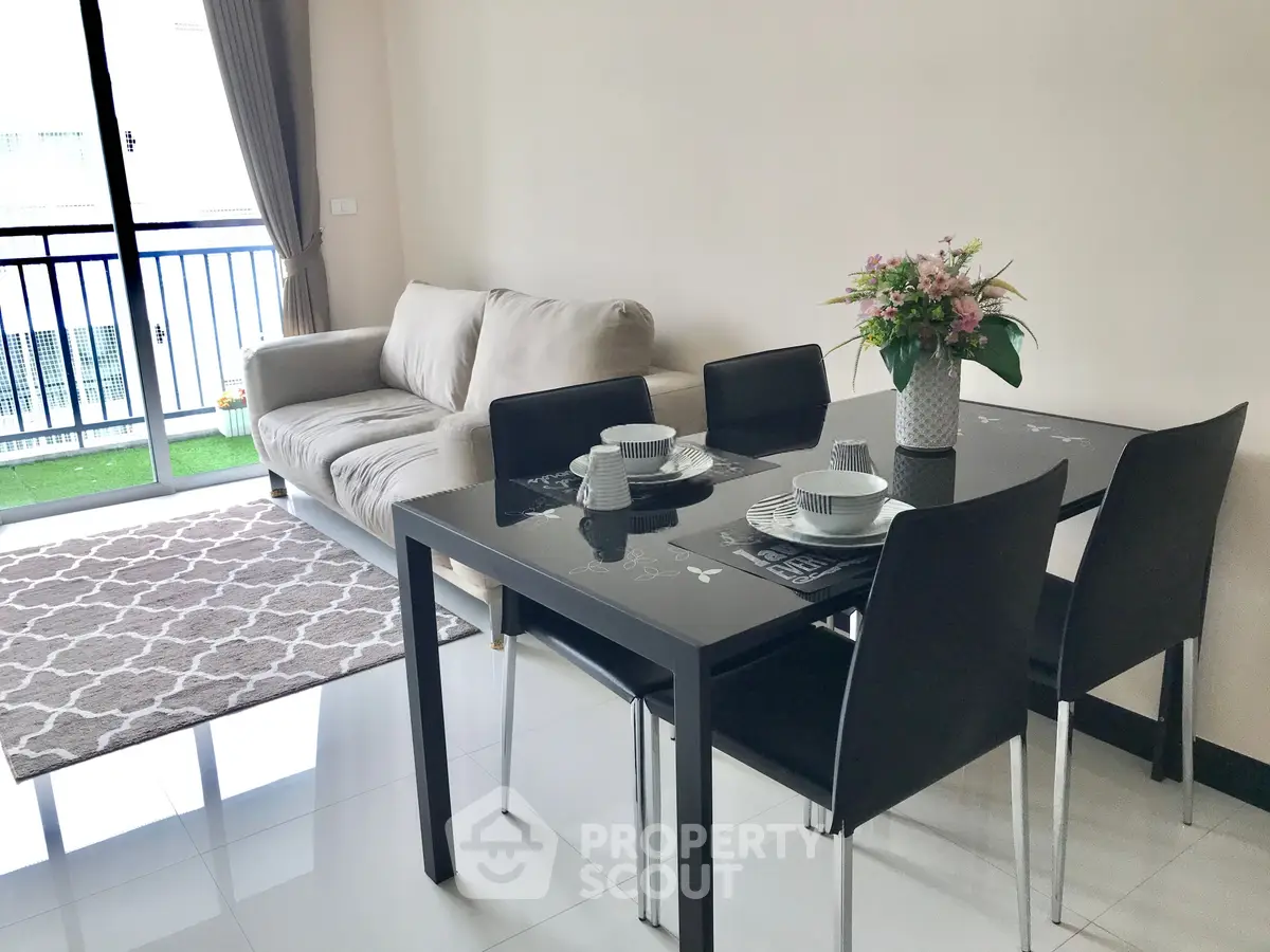 Modern living room with dining area and balcony access, featuring sleek furniture and natural light.