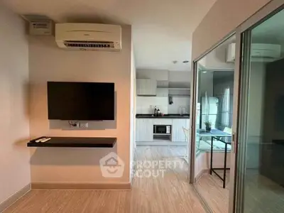 Modern apartment interior with wall-mounted TV and sleek kitchen design.