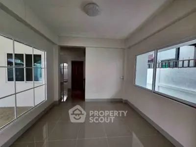 Spacious empty room with large windows and glossy tiled floor, perfect for customization.